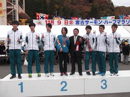 1、2、3と番号が書かれた表彰台の上に立つ市長と7名の選手たちの記念写真