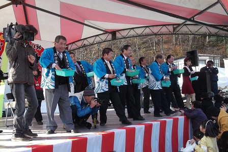 法被を着た市長や関係者の方々が舞台の上から餅まきをしている写真