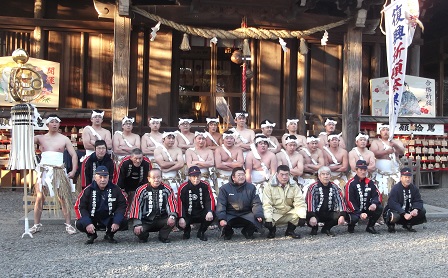 横山八幡宮の拝殿の前で、両端で纏と幟を持っている19人が下帯姿でしめ縄にけんだいワラを垂らし、8人が消防団の法被姿で、コート姿の山本市長と他1名が3列に整列して撮影した写真