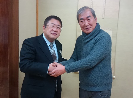 市長と青いセーター姿の桂文枝師匠が両手で握手を交わしている写真