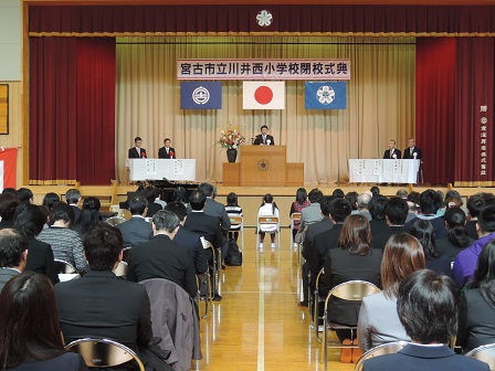 宮古市立川井西小学校閉校式典と書かれた横断幕があるステージに来賓の方々が座っている中、演台であいさつをしている市長と、座って聞いている在校生と多くの参加者の方々の写真
