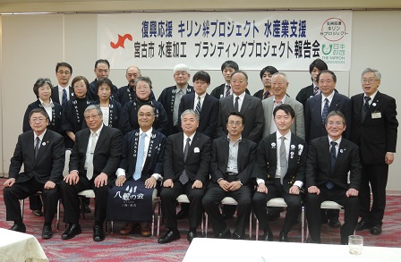 復興応援キリン絆プロジェクト水産業支援、宮古市水産加工プランティングプロジェクト報告会と書かれた横断幕の下で参加されたキリンビール株式会社、日本財団の方々が3列に並んで撮影した写真