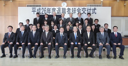平成26年度退職者辞令交付式と書かれた横断幕の前に、市長を中心にして退職される方々が4列に整列して撮影した写真