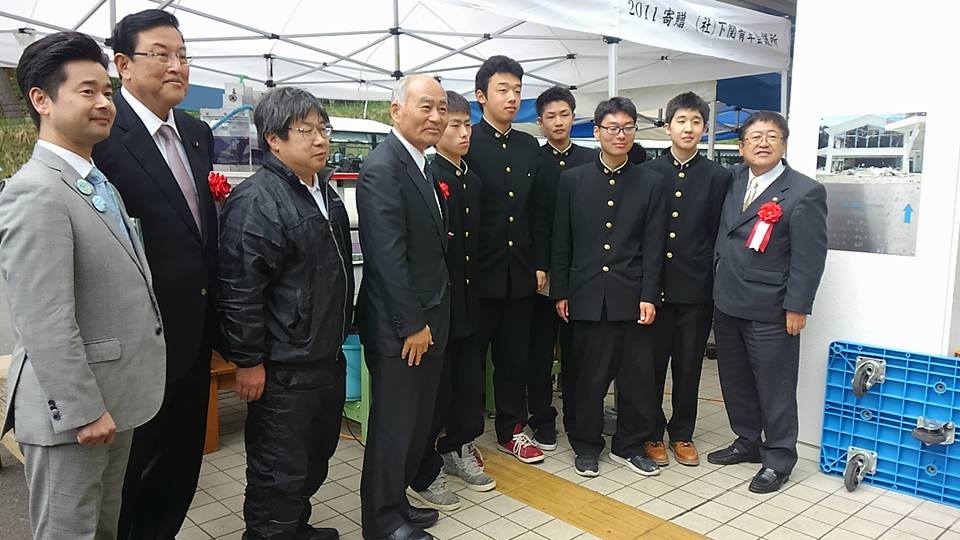 制服を着た男子学生と市長、関係者の方々が並んで立つ記念写真