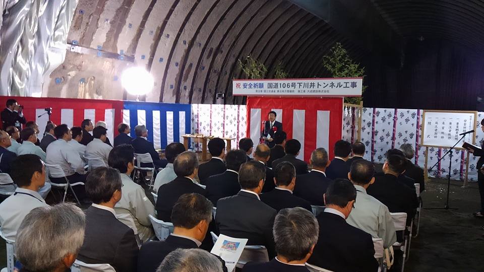 紅白幕の前に立つ市長の向かい側で、パイプ椅子に座っている関係者の方々の写真