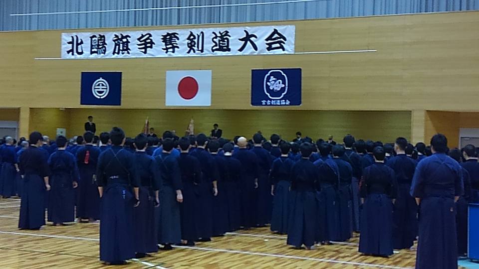 「北鷗旗争奪剣道大会」と書かれた横断幕や旗が掲げられた会場で、剣道着を着た選手たちが並んで立っている写真