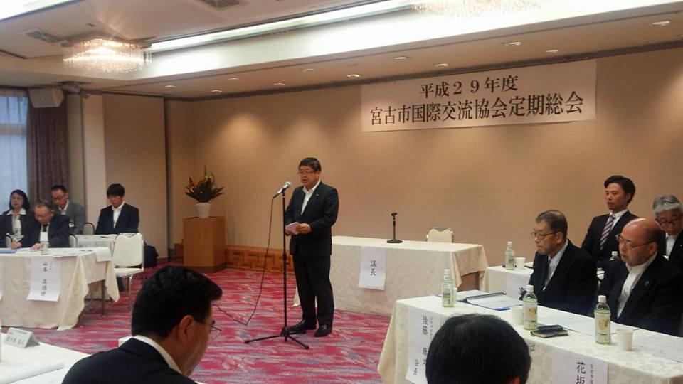 「平成29年度 宮古市国際交流会定期総会」と書かれた紙が貼られた壁の前で、スタンドマイクに向かい話をする市長の写真