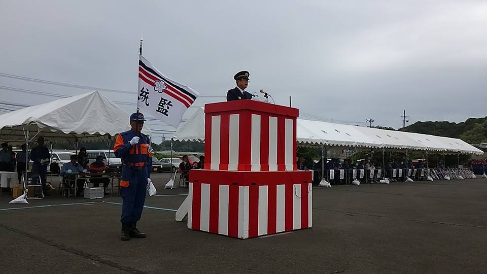 紅白に塗装された演台の上に立ち、制帽を被った市長がスタンドマイクに向かい話をしている写真