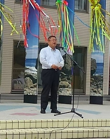 吹き流しが飾られた場所で、スタンドマイクに向かい話をする市長の写真