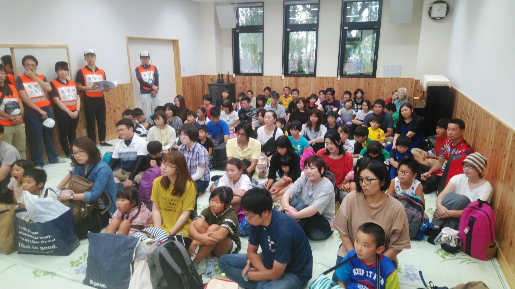 部屋の床に座って話を聞く様子の宮古市民の方々の写真