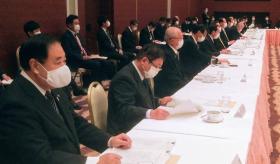 テーブルクロスが敷かれた長いテーブルの席に着き、手元の資料を見る様子の市長と、その周りで席に着く関係者の方々の写真