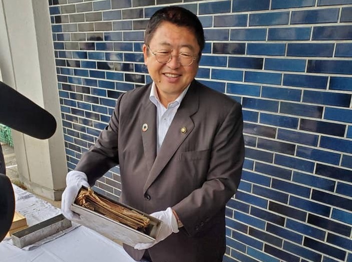 白い手袋を着けてタイムカプセルを持つ市長の写真
