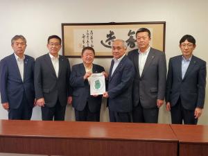 壁掛けの書の前で、市長と男性で提言書を持ち、両脇に男性2名ずつが立って撮影した写真