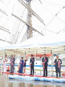テント内に敷かれたレッドカーペットの上で市長と男女4名でテープカットをしている写真