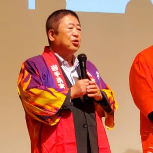 赤い法被を着た市長がマイクを持ち、話をしている写真