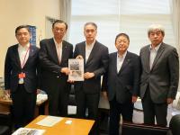 窓側の場所で男性2名で要望書を持ち、その横に市長を含む男性3名が並んで撮影した写真