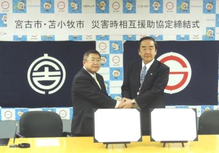 協定式画像：握手を交わす山本宮古市長と岩倉苫小牧市長