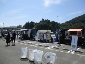 青空の下、駐車場にキッチンカーが3台並んでいる写真