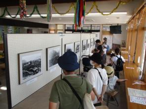 室内に展示されている白黒の写真を見つめる人達の写真