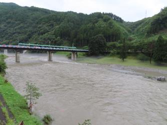 濁った水が流れる川とその川にかけられた橋の写真