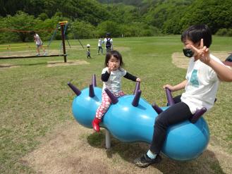 水色のスイング遊具に女の子と男の子がまたがっている写真