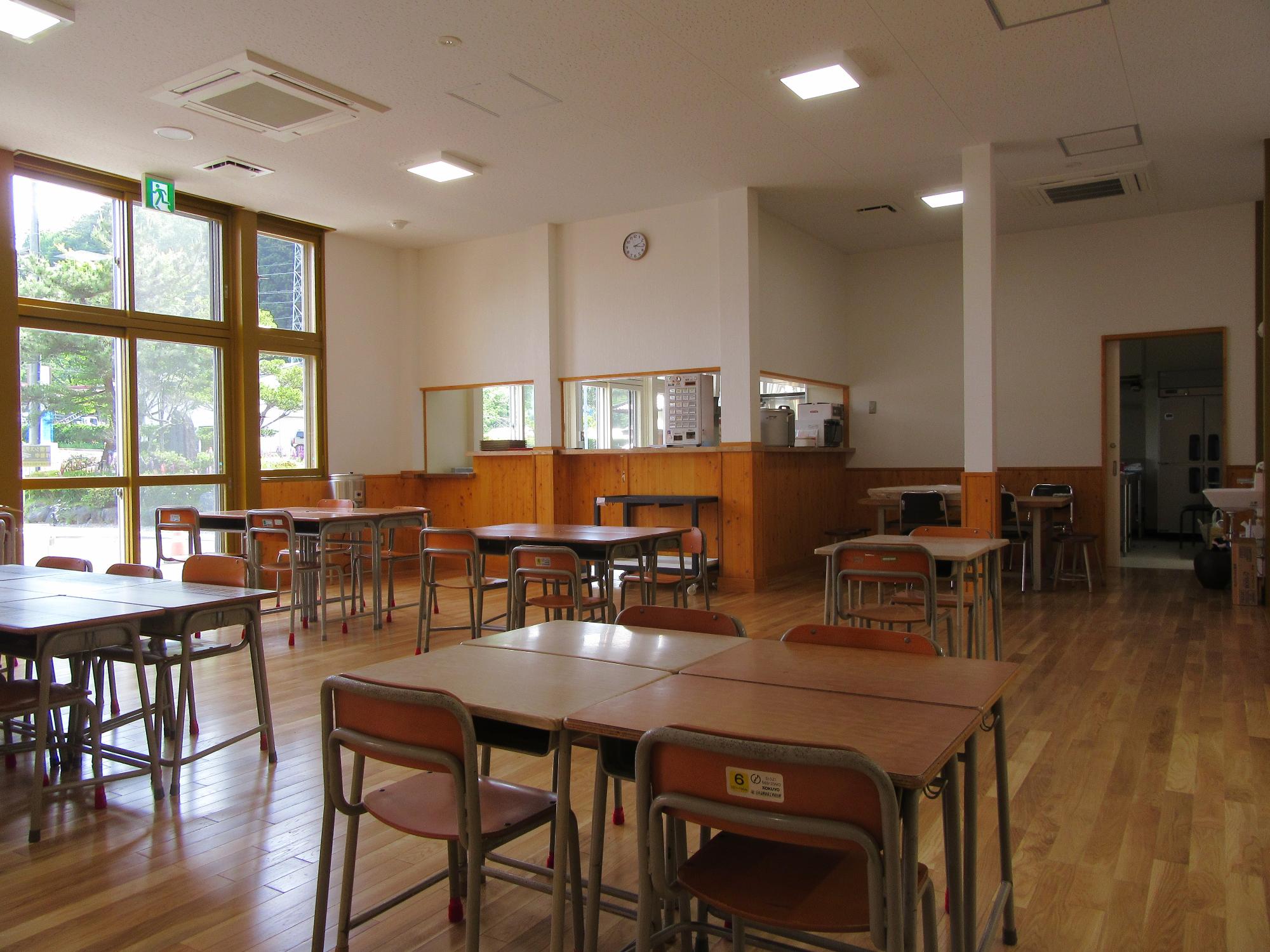 学校で使用されていた机といすが向かい合って6人が1組、4人が3組、2人が1組で座れるように設置されたフードコートの様子を撮影した写真