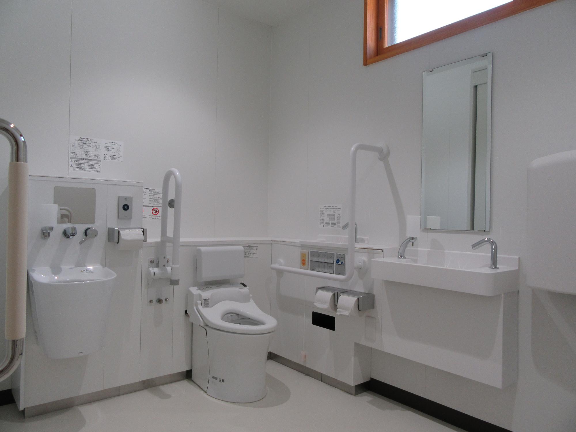 鏡、手洗器、手すりも完備され車いすの方にも広くて使いやすい清潔なトイレを撮影した写真