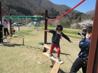 ジグザグに設置された細い板の上をバランスをとりながら男の子が歩いている写真