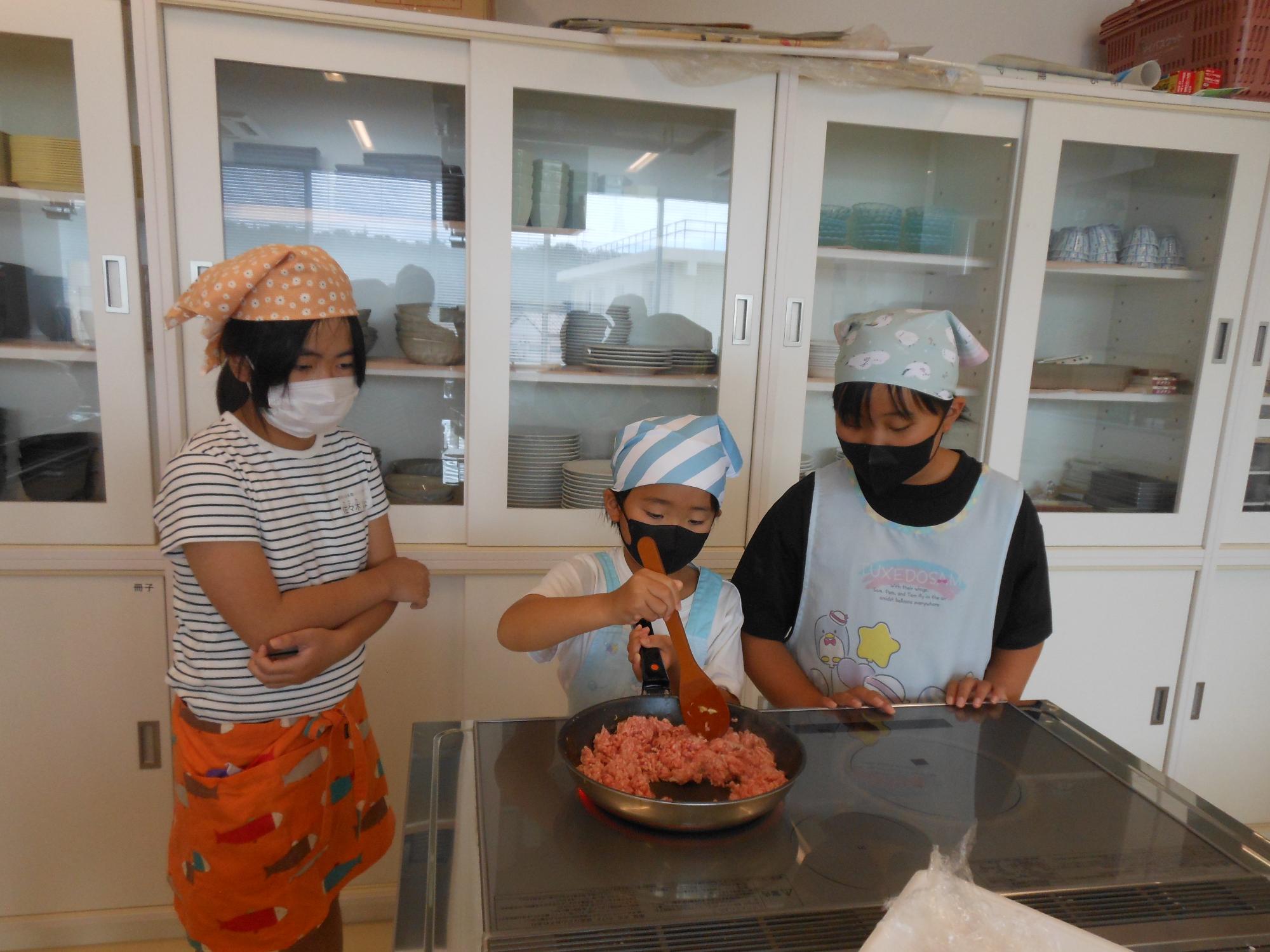 女の子がひき肉を炒めている写真
