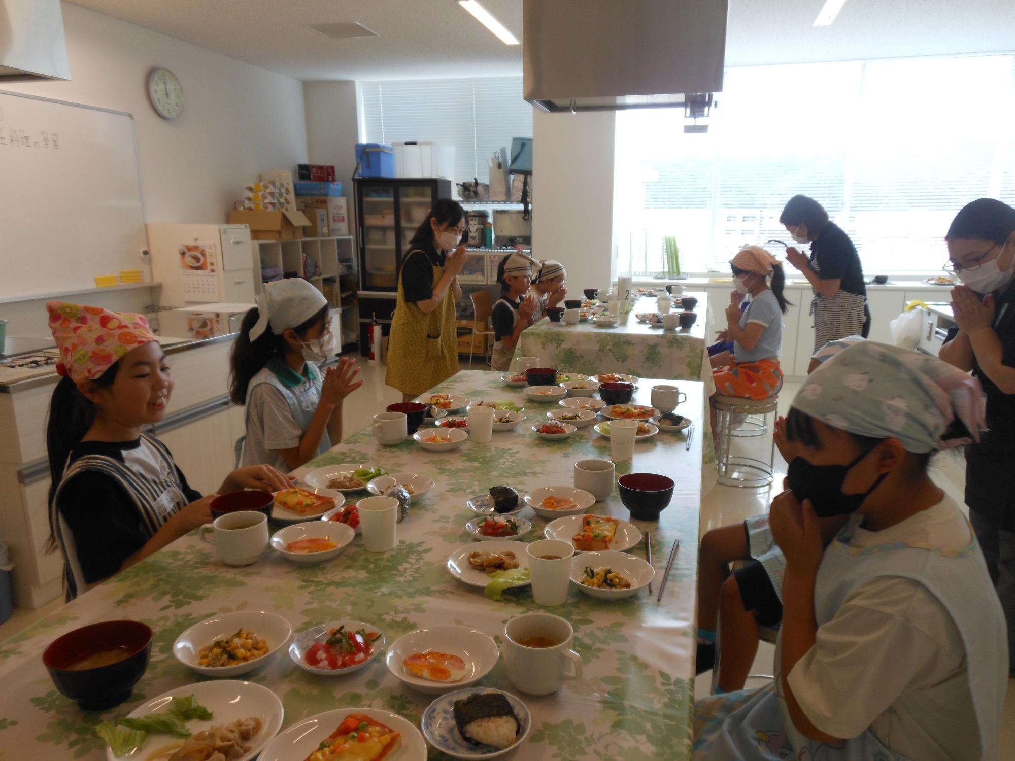 調理実習で完成した料理を前にいただきますをしている写真
