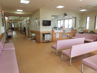 ピンク色の長椅子が複数設置された待合室の写真