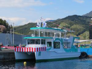 赤色と白色の縦じまの幕を前方につけ、海に着水した宮古うみねこ丸を斜め前から写した写真