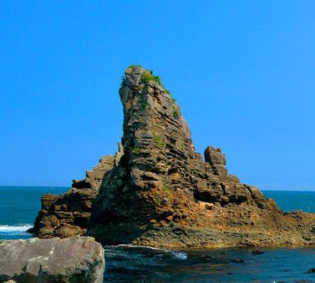 青い海の中にある、羅賀層と田野畑層が重なり合った女岩の写真