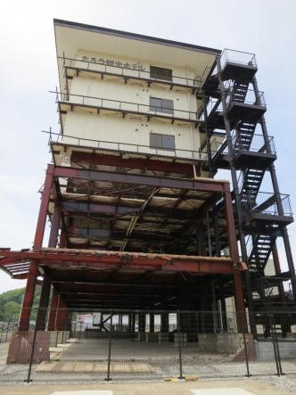 1.2階部分の鉄骨が剥き出しの状態になった、たろう観光ホテルの外観を下から撮影した写真