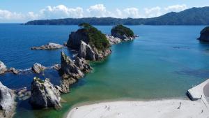 海面から顔を出すいくつもの岩と一部の岩に生える緑色の木々、そして穏やかな波の海が美しい浄土ヶ浜を上空から写した写真