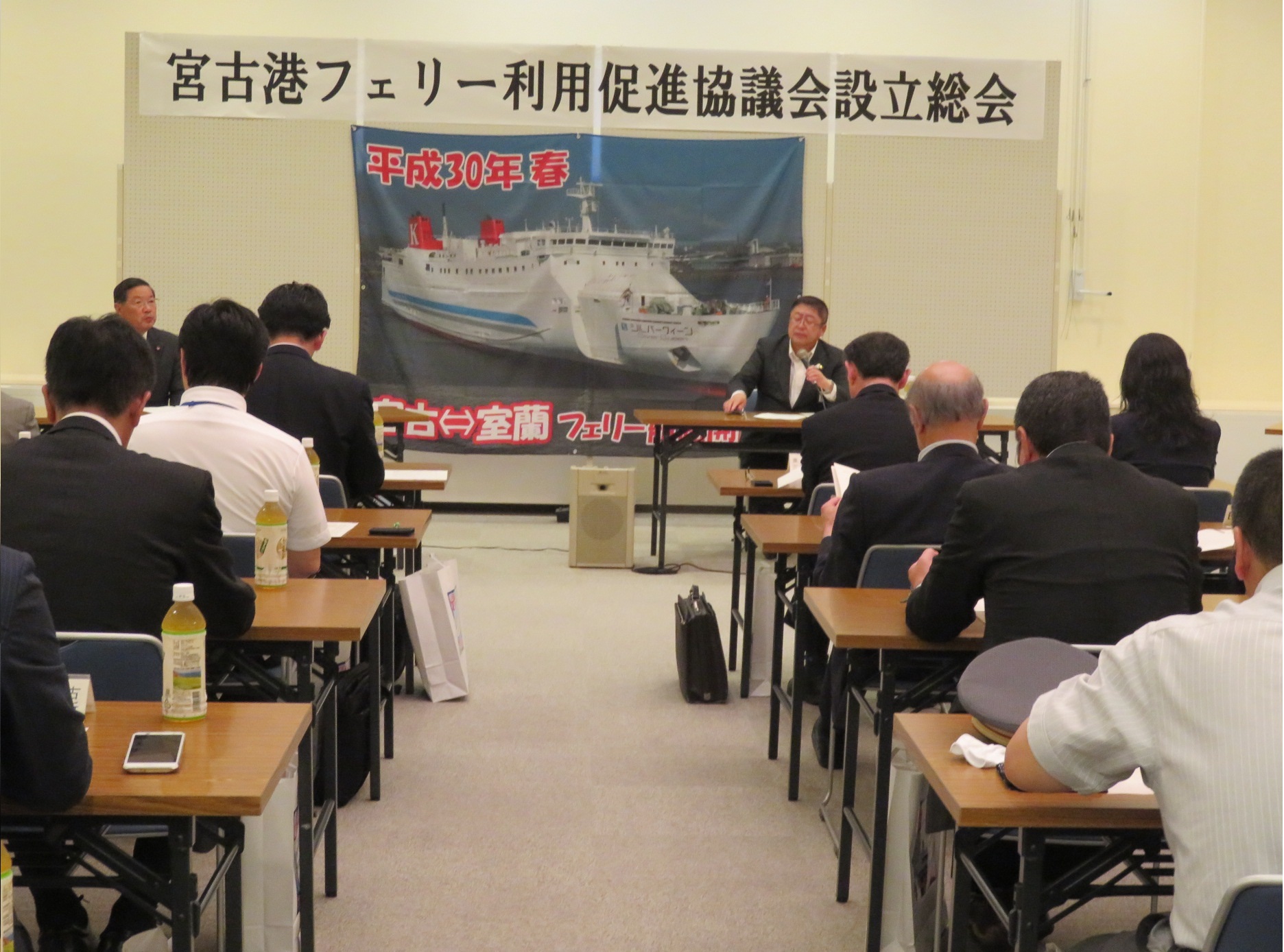 宮古港フェリー利用促進l協議会設立総会と書かれた横断幕が掲げられ参加者の人たちが長机に座り会議に参加している様子を写した写真