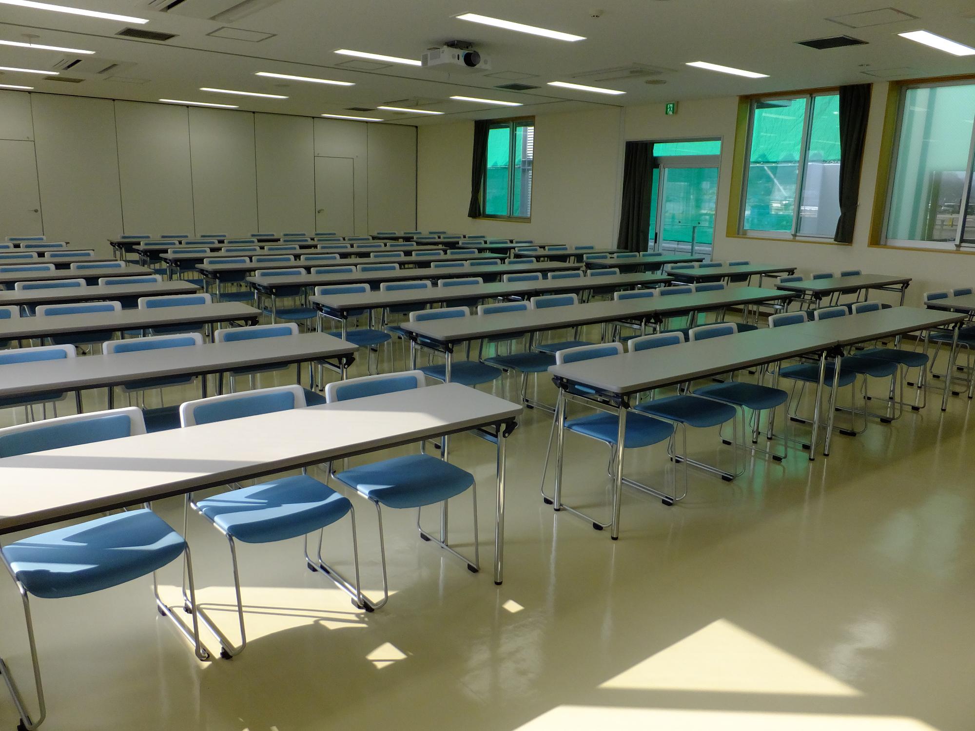 右側中央に出入り口と窓が設けられ、3人掛けの長机が3列に設置された第2会議室の写真