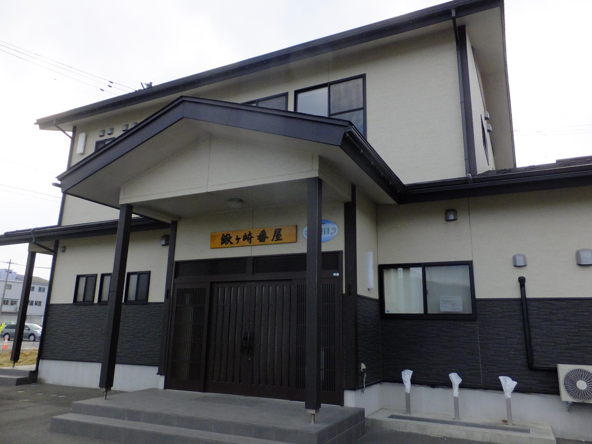 黒と白の外壁で、出入り口の両開きの引き戸の上に「鍬ヶ崎番屋」と書かれた看板が設置された建物外観の写真