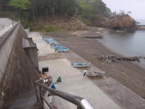 海に向かって7艘の船が海岸横のコンクリートの上に縦に並んでいる様子を撮影した写真