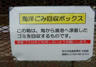 海洋ごみ回収ボックス この箱は、海から漁港へ漂着した ゴミを回収するものです。 漂着ゴミ以外に利用しないようお願いします。と書かれた立て札の写真