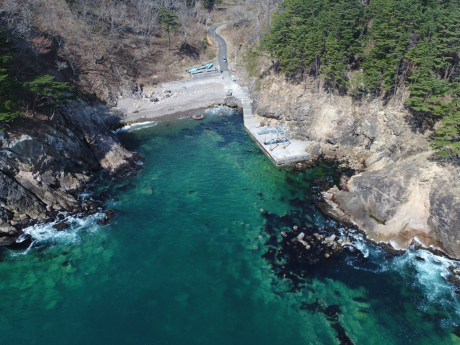 岩肌の見える海岸にある大浜地区の港を上空から写した写真