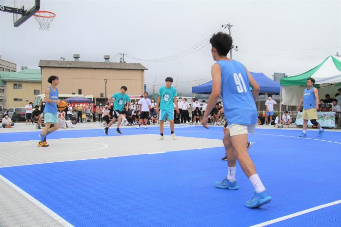 スリーオンスリーの鮮やかなブルーのバスケットコートで試合をしている写真