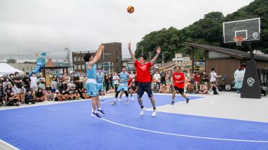 3オンスリーの試合が行われ水色のユニフォーム姿の人がシュートをうっている写真