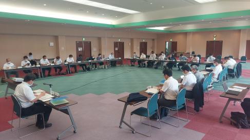 床がピンク、赤、緑と色とりどりになっている室内に長机が並べられ、関係者の人たちが座って会議がおこなわれている様子を写した写真