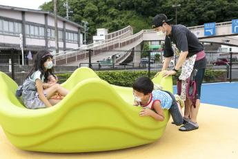 気に鳥色の座れる遊具で女の子と男の子が乗り込みお父さんらしき人が動かそうとしている写真