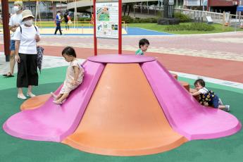 ピンクとオレンジ色の花びらの形をした滑り台で小さな子供達が遊んでいる写真