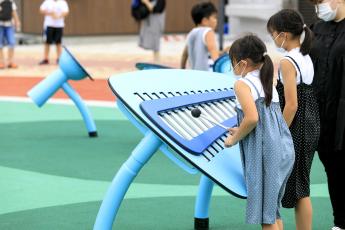 もっきんのような形をした遊具で女の子が2人でたたきながら遊んでいる写真