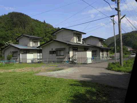 手前に公園があり、背景には山がある2階建て刈屋日向団地住宅の外観写真
