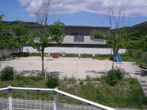 山口団地住宅前に滑り台、シーソーなどの遊具が設置された児童遊園の写真