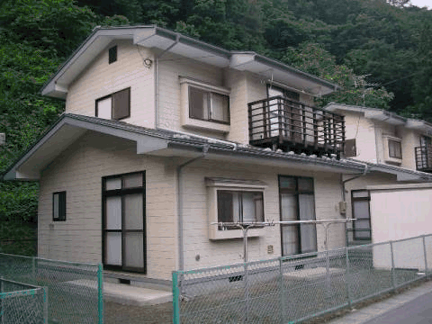 フェンスで仕切られ、ベージュ色の外壁の2階建て戸建住宅の外観写真